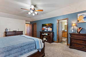 Bedroom with ensuite bath, light colored carpet, a ceiling fan, and a closet
