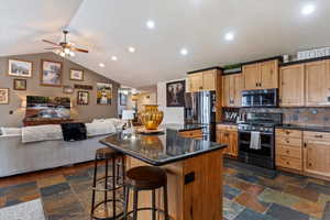 Kitchen featuring open floor plan, stainless steel appliances, a kitchen island, a breakfast bar, and a ceiling fan