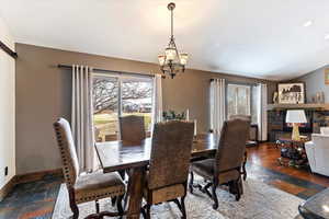 Dining space featuring stone tile flooring, vaulted ceiling, and a chandelier