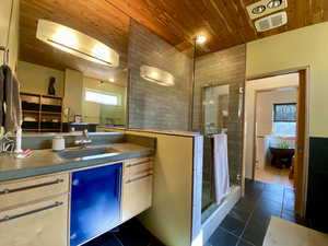 Kitchen featuring light wood finish cabinetry, dark tile patterned flooring, wood ceiling, and dark countertops