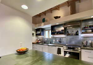 Kitchen featuring stainless steel electric stove, dark countertops, dishwasher, beamed ceiling, and open shelves