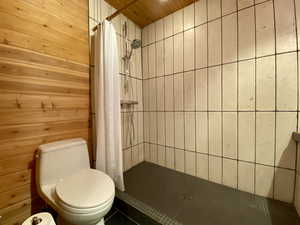 Full bathroom featuring a stall shower and wooden walls
