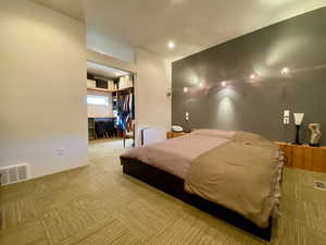 Bedroom featuring light colored carpet, a spacious closet, and recessed lighting