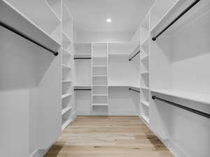 Walk in closet with light wood finished floors