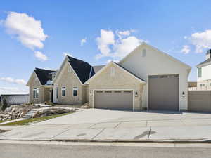 View of front of home featuring an attached garage, driveway, and stone siding