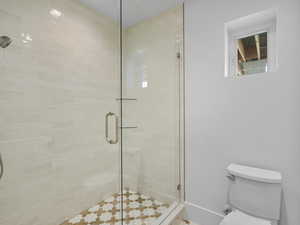 Full bathroom featuring toilet and a stall shower