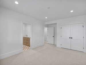 Unfurnished bedroom with light colored carpet, recessed lighting, ensuite bathroom, and a closet