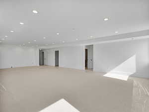 Below grade area with light colored carpet and recessed lighting