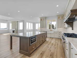 Kitchen with two tone cabinetry, light quartz counters, a center island, a breakfast bar area, and light wood-style floors