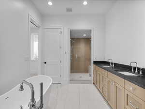 Bathroom featuring recessed lighting, double vanity, a freestanding tub, and a shower stall