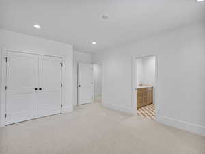 Unfurnished bedroom with recessed lighting, light carpet, ensuite bath, and a closet