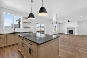Kitchen with decorative backsplash, suspended lighting, a center island, a fireplace, and open floor plan