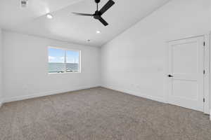 Carpeted empty room with lofted ceiling, a ceiling fan, and recessed lighting