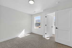 Unfurnished bedroom with light carpet and a mountain view