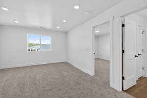 Empty room with dark colored carpet and recessed lighting