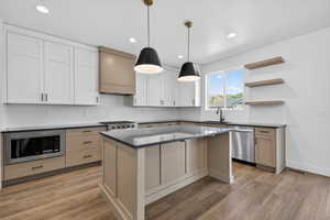 Kitchen featuring a kitchen island, hanging light fixtures, light wood finished floors, and open shelves