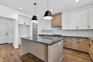 Kitchen with a center island, tasteful backsplash, stainless steel gas stove, dark wood-style flooring, and pendant lighting