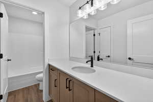 Bathroom featuring vanity, dark wood-type flooring, and shower / bath combination