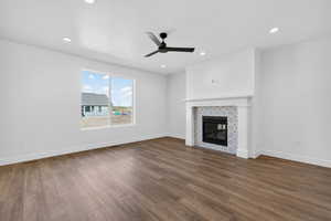 Unfurnished living room featuring ceiling fan, dark wood-style floors, a tiled fireplace, and recessed lighting