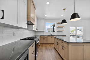 Kitchen with stainless steel range with gas stovetop, a center island, dark wood-style flooring, open shelves, and hanging light fixtures