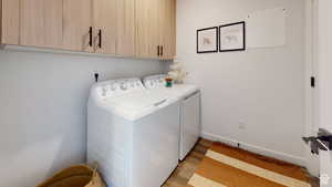 Laundry room featuring cabinet space, light wood-style flooring, and washer and dryer