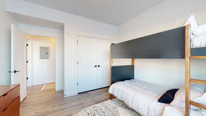 Bedroom featuring light wood-type flooring, electric panel, and a closet