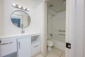 Full bath with vanity, light tile patterned floors, and shower / tub combination