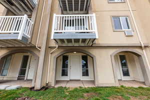 Property entrance with stucco siding and a wall mounted AC