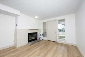 Unfurnished living room with a brick fireplace, light wood-style flooring, and a textured ceiling