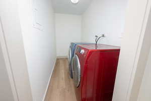 Laundry room featuring light wood-type flooring, washer and dryer, and electric panel