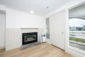 Unfurnished living room with light wood-type flooring, a glass covered fireplace, and plenty of natural light