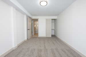 Unfurnished bedroom with a closet, a textured ceiling, and light carpet