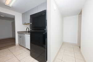 Kitchen featuring freestanding refrigerator, light tile patterned floors, dishwasher, light countertops, and a textured ceiling