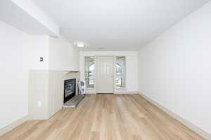 Unfurnished living room featuring light wood-style flooring and a brick fireplace