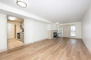 Unfurnished living room featuring light wood finished floors and a glass covered fireplace
