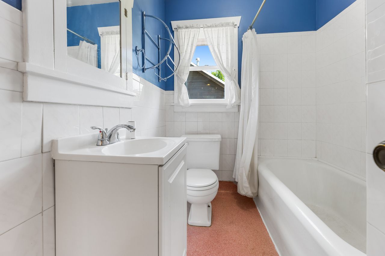 Bathroom with vanity, shower / bathtub combination with curtain, tile walls, and a wainscoted wall