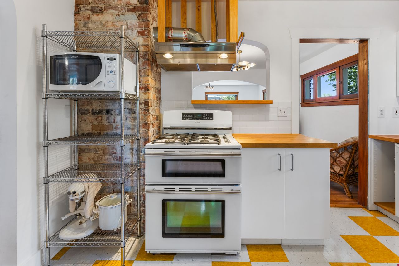 Kitchen featuring white appliances, light floors, tasteful backsplash, white cabinetry, and wood counters