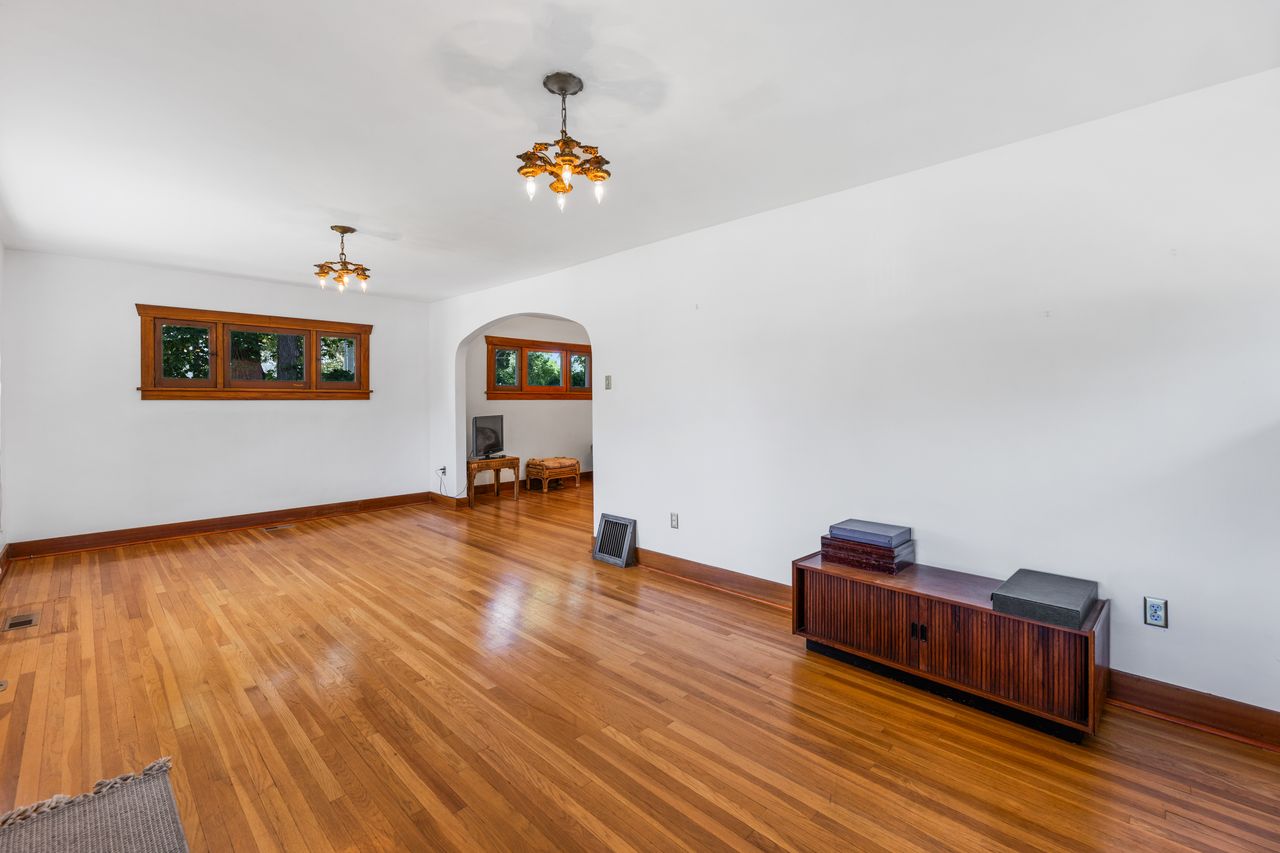 Unfurnished room featuring arched walkways, light wood-style flooring, and a chandelier