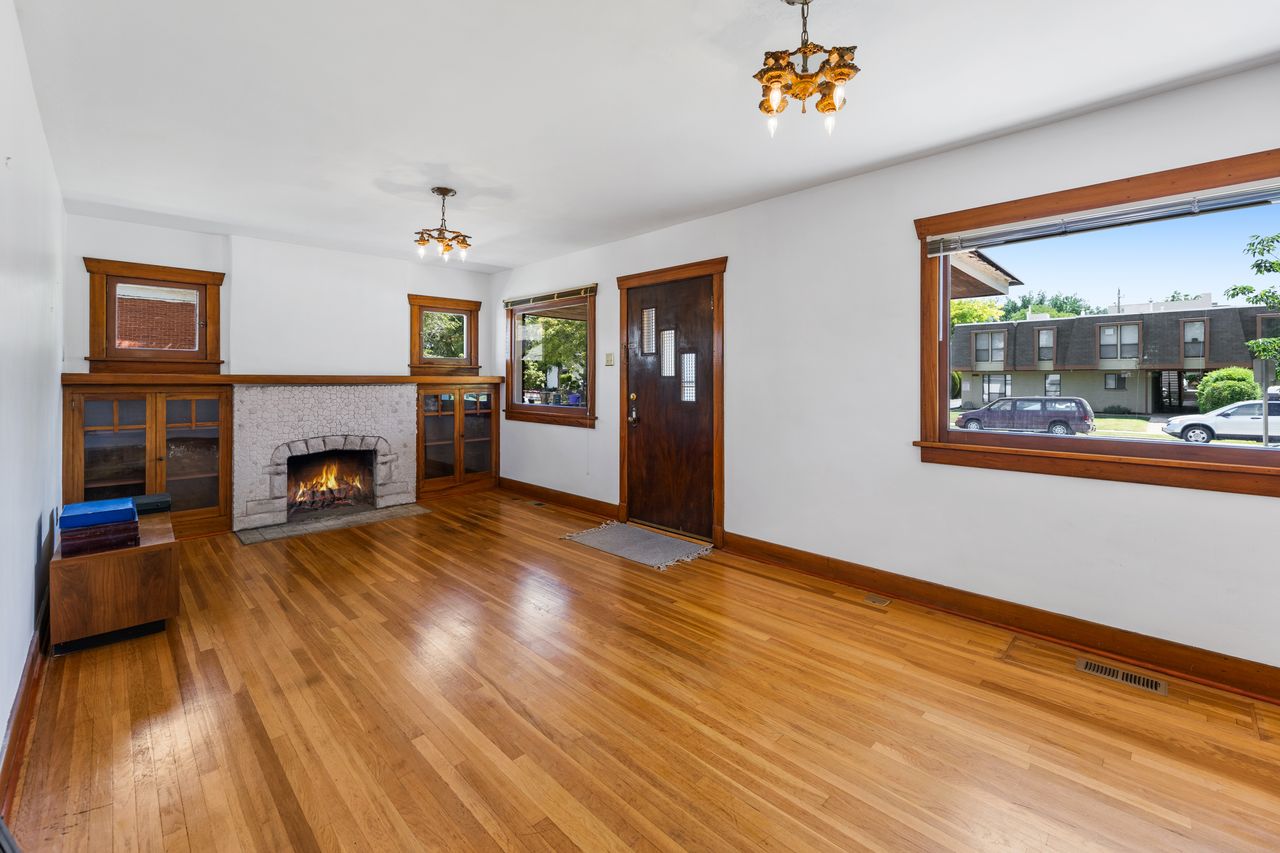 Unfurnished living room with light wood-style flooring, suspended lighting, and a fireplace with flush hearth
