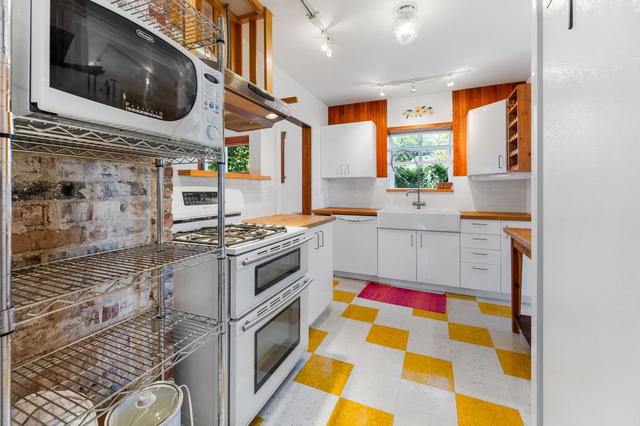 Kitchen featuring light floors, white appliances, white cabinets, and healthy amount of natural light