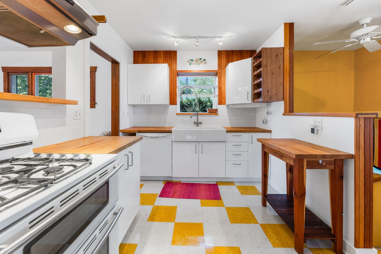 Kitchen with light flooring, white appliances, butcher block counters, white cabinets, and ceiling fan