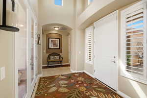 Entryway featuring arched walkways, a high ceiling, and light tile patterned flooring