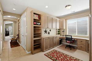 Office with built in desk, light carpet, arched walkways, recessed lighting, and light tile patterned floors