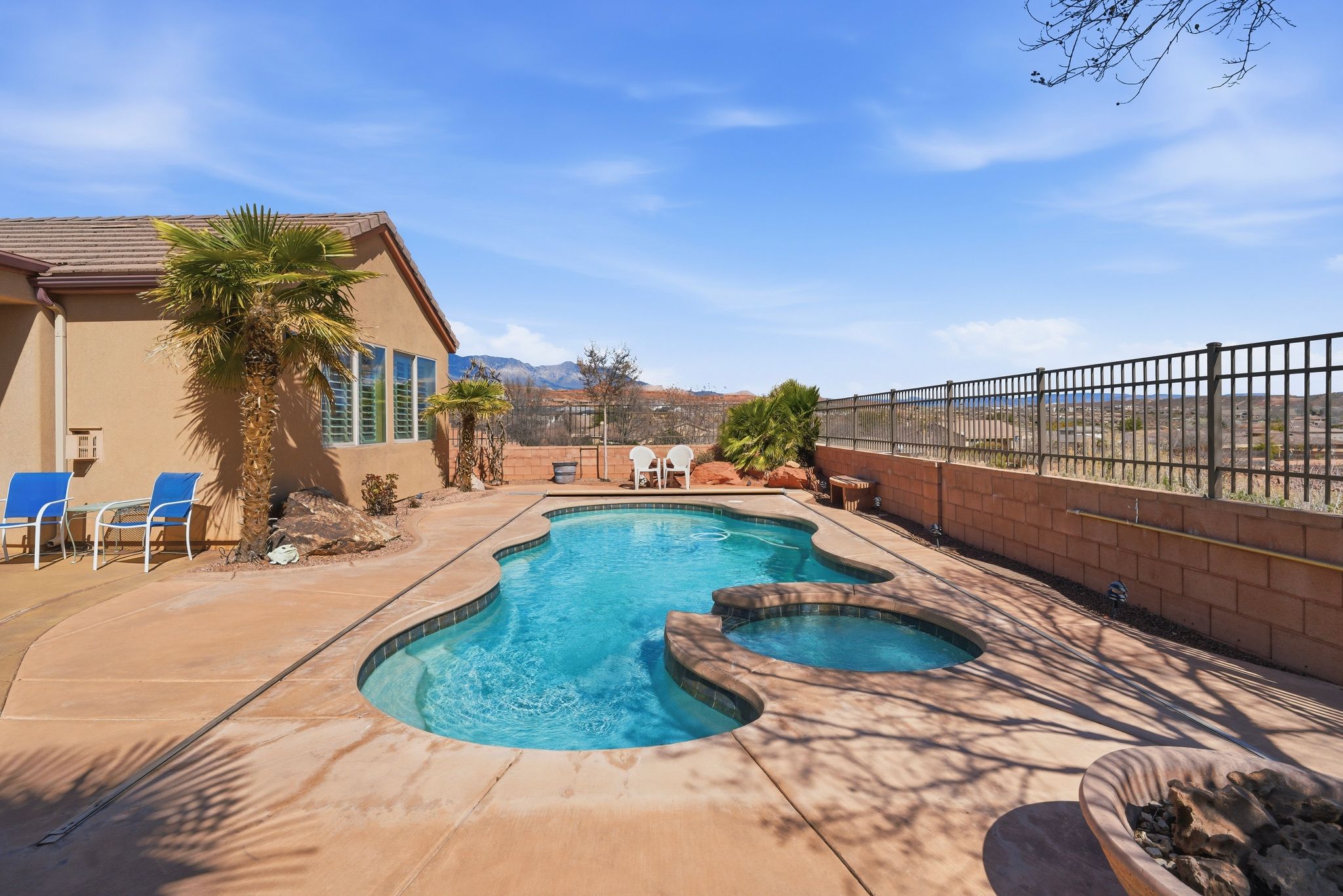 Combined pool / hot tub with a fenced backyard and a patio