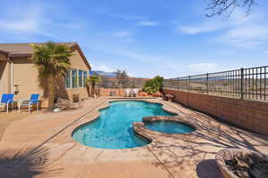Combined pool / hot tub with a fenced backyard and a patio