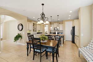 Dining space with arched walkways, light tile patterned floors, and suspended lighting