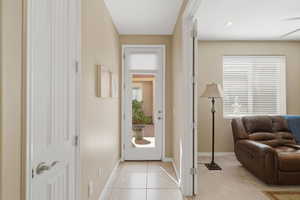 Hall with light tile patterned flooring and light colored carpet