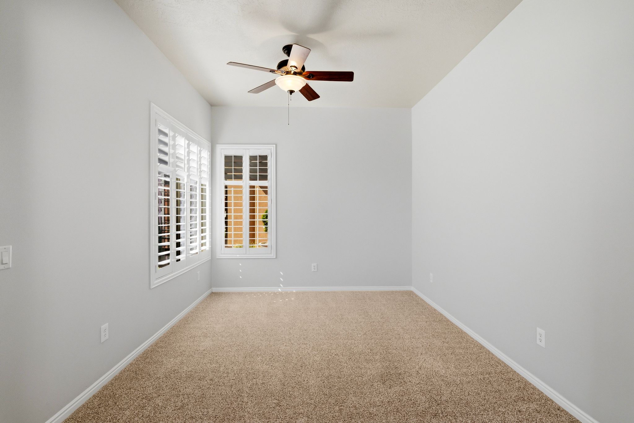 Spare room featuring a ceiling fan and light colored carpet