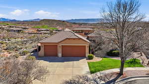 View of front of property with an attached garage, stucco siding, driveway, a tiled roof, and a mountain view
