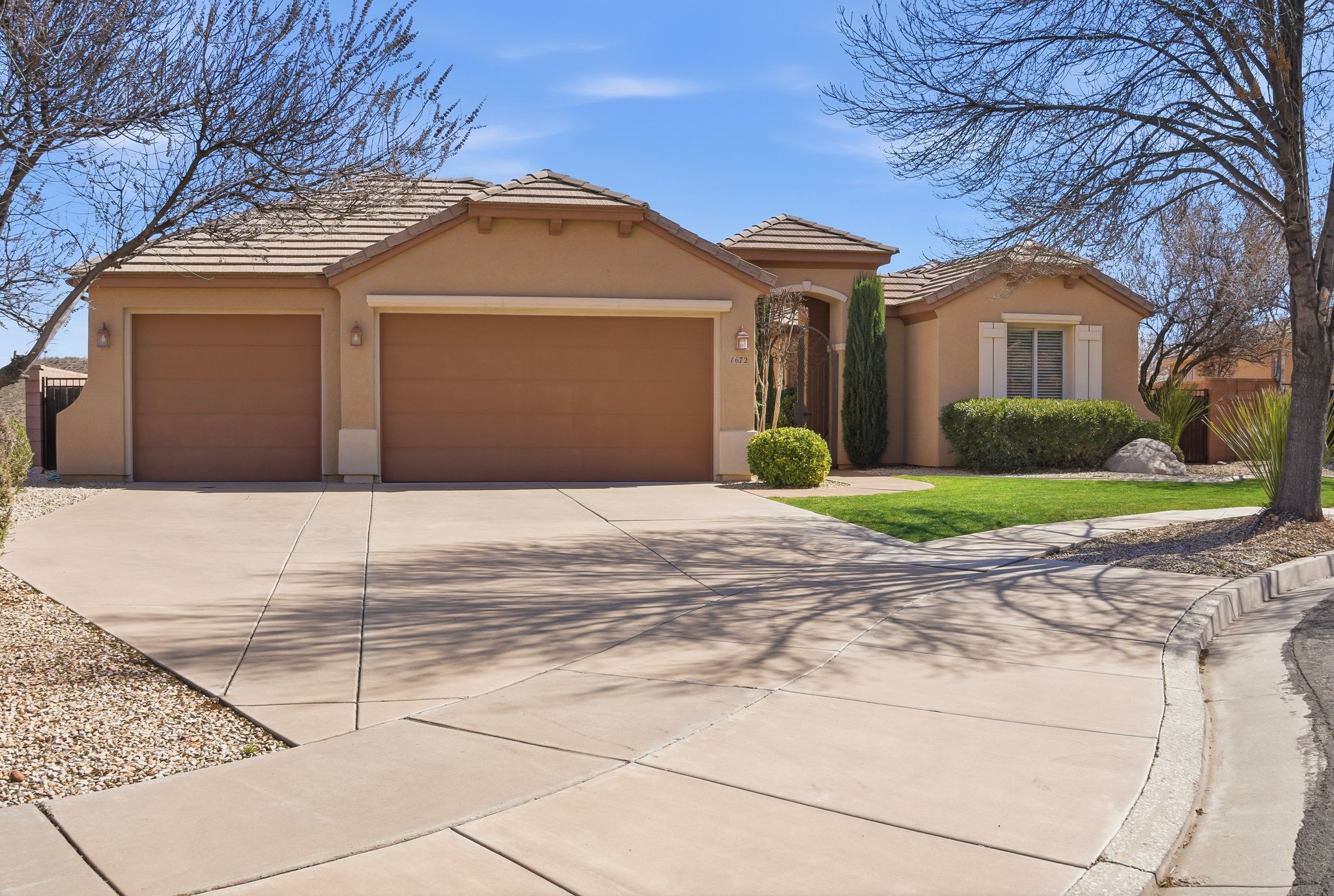 Mediterranean / spanish-style house featuring driveway, stucco siding, a garage, a tiled roof, and a front lawn